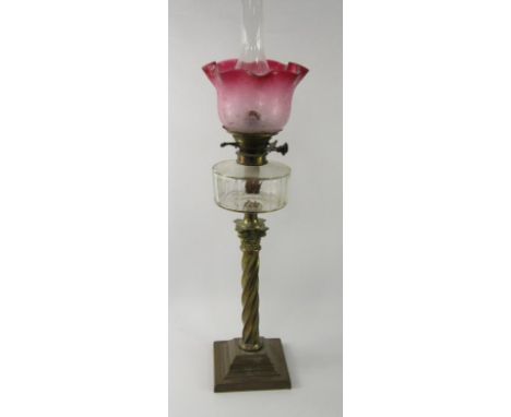 A Duplex Corinthian column brass oil lamp, with a faceted, clear glass reservoir and floral etched cranberry glass shade, 81c