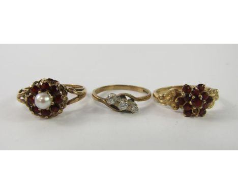 A 9ct gold garnet and pearl ring, size O, 9ct gold and garnet flower head ring, size L, and a gold and diamond three stone ri