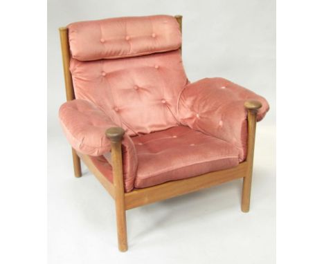 A 1970's teak framed armchair, upholstered in red button back draylon, on cylindrical legs. The upholstery in this lot does n