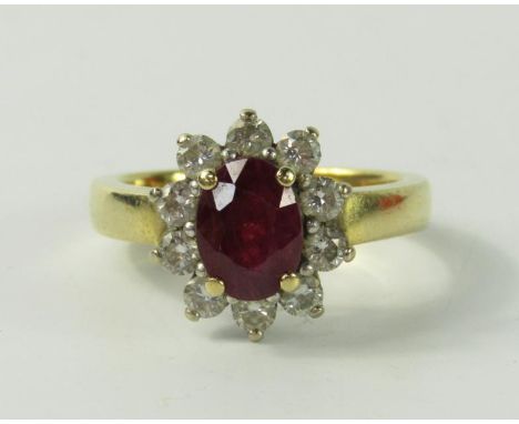 An 18ct gold ruby and diamond ring, the oval cut ruby in a surround of ten diamonds, ruby approx 2.1cts, diamonds 0.8cts, siz