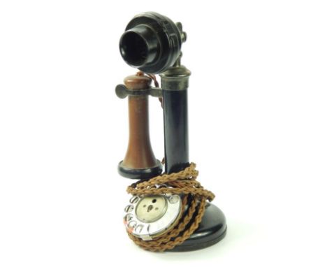 A black and brown metal and Bakelite candlestick telephone.