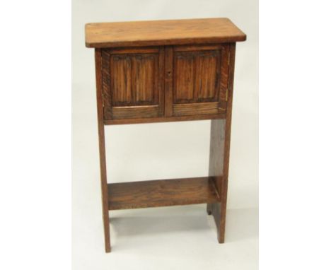 An oak student's bureau, with linenfold panel sides and doors, with shelf under, believed to have been made from a pew from S