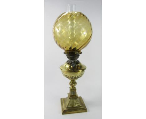 A Veritas late 19thC fluted brass oil lamp, raised on a stepped square base with a spiral fluted amber glass globe shade, 64c