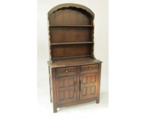 A Priory oak dresser, the domed two shelf Delft rack over two drawers with panelled cupboards below, raised on fluted straigh