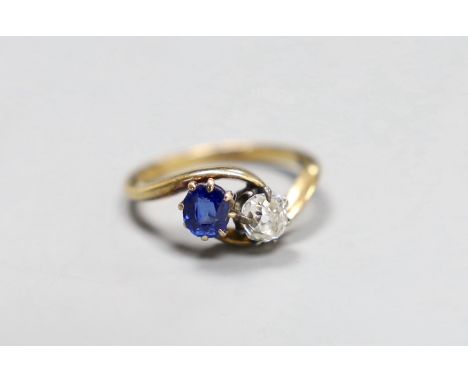 An early 20th century 18ct gold, sapphire and diamond two stone cross-over ring, size L, gross 3.2 grams