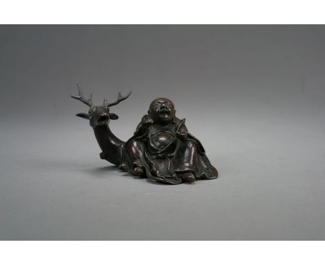 A Chinese bronze figural brush rest18th/19th CenturyModelled as a seated lohan with recumbent deer.11cm long