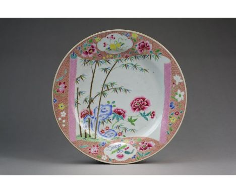 A Chinese famille rose dishQianlongDecorated with peony blooms with leafy bamboo and rockwork, within a scroll-form reserve b