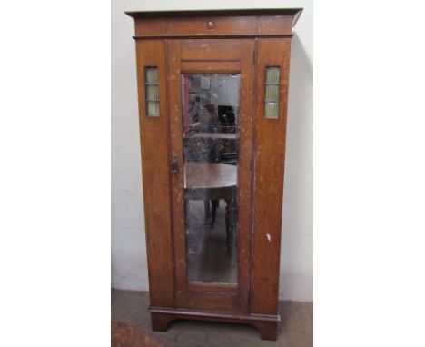 An Edwardian oak wardrobe, the moulded cornice above a mirrored door on bracket feet