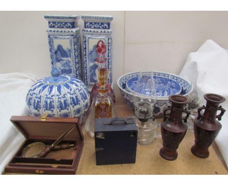 Glass oil lamps together with coloured glass decanters, blue and white vases and bowls, magnifying glass, camera, etc