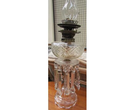 A Victorian cut glass oil lamp with lustre drops on spreading feet