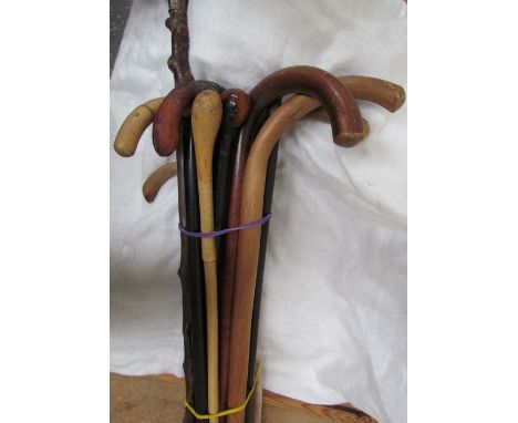 A white metal topped walking stick together with a collection of walking sticks 