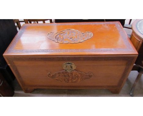 A carved Chinese camphor wood coffer decorated with figures in a landscape on bracket feet