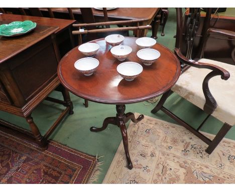 A George III flamed mahogany dished circular tilt top wine table on turned and wrythen carved column over a tripod base