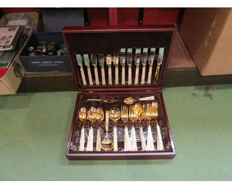 A gilt stainless steel set of cutlery with cream enamel handles