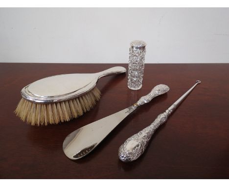 A silver backed hair brush, silver topped container, button hook and shoe horn with silver handles (4)