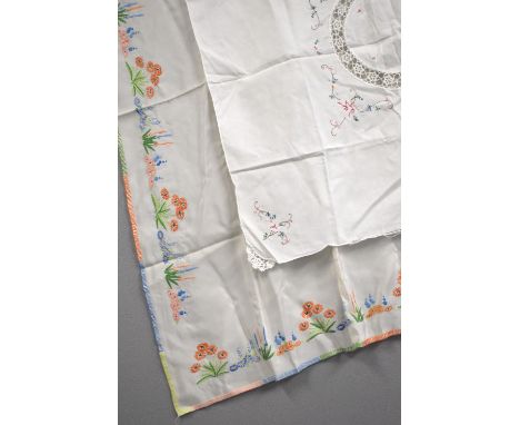 Two pieces of hand embroidered and cross-stitched tablecloths, featuring beautiful examples of floral hand crafted stitching.