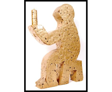 A contemporary designed cork constructed sculpture lamp. The lamp depicting a person sat upon a stool holding a candle, all b