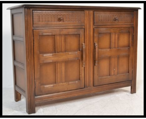 A vintage 20th Century beech and elm wood Ercol style cabinet sideboard raised on block legs with geometric moulded front. Tw