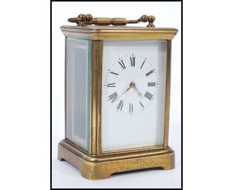 An early 20th Century brass bound carriage clock having roman numerals to the chapter ring and faceted hands, a swing handle 