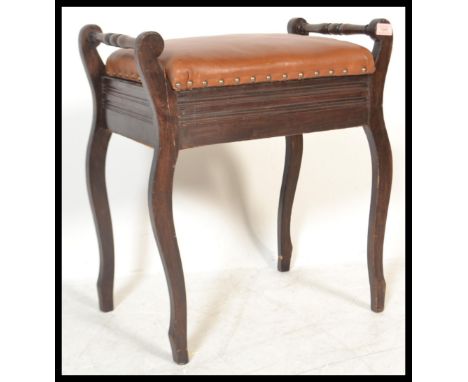 An early 20th Century Edwardian mahogany piano stool, with end raised handles, over cupboard base, upholstered in leather wit
