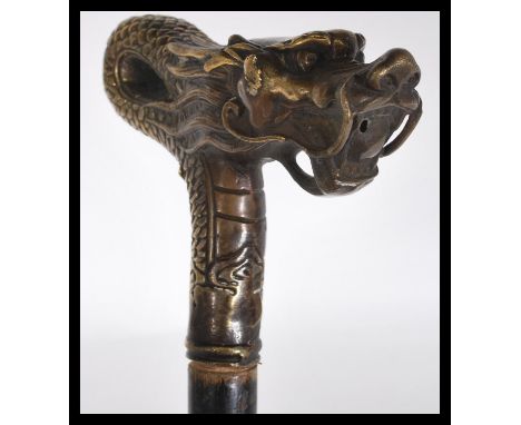 A 19th Century Chinese walking stick cane having a tapering ebonised shaft with bronze figural handle in the form of a dragon