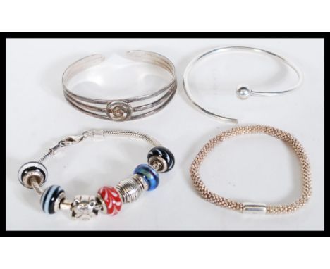 A selection of silver bracelets to include a split bangle, a Links of London bracelet, a charm bracelet with glass beads and 