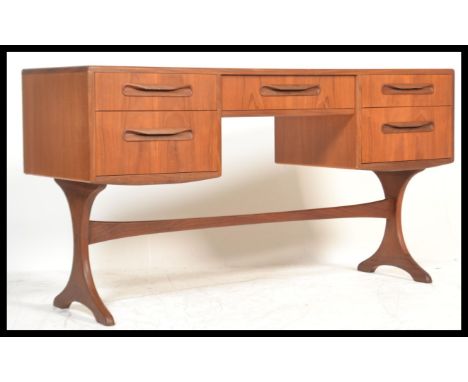 A vintage retro G-Plan 20th Century teak writing table being desk raised on shaped supports with twin banks of drawers having