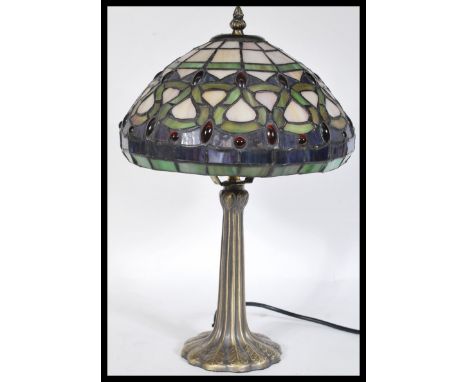 A 20th Century twin bulb Tiffany inspired table lamp, the cast base of Art Nouveau taste having a bronzed effect finish, surm