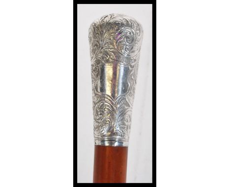 A malacca walking stick cane having a silver white metal knop to the top with foliate decoration and a unmarked cartouche pan