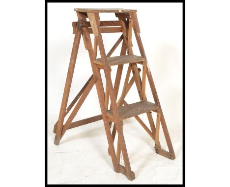A good early 20th century Industrial wooden a-frame folding ladder having trestle / lattice worked sides with steps to centre