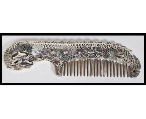 A Chinese 20th Century silver plated comb in the form of a dragon having scrolled decoration. Measures 6.5cm wide.