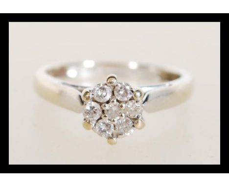 A hallmarked 18ct white gold diamond cluster ring having approx 25pts of diamonds in a claw setting. Weighs 3.3 grams size K.