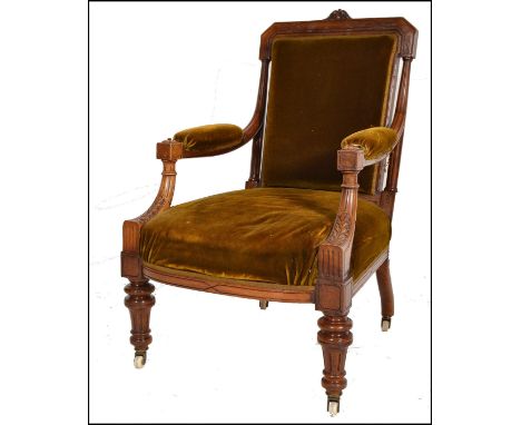 A Victorian 19th century mahogany library armchair being raised on reeded, turned legs with white ceramic castors. Overstuffe