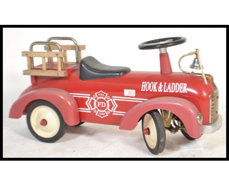 A children's fire ride along truck toy in the form of a fire truck reading 'Hook and Ladder' of metal construction with a bel