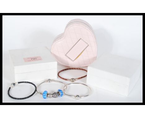 A silver Pandora bracelet with four charms two being blue glass along with a Pandora bangle bracelet and two leather chord br