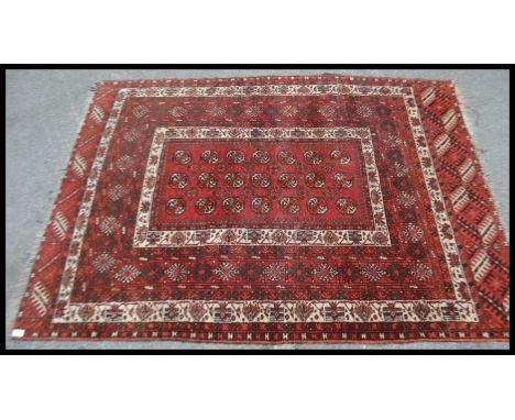 A vintage early 20th Century Persian Islamic floor carpet rug having a red ground with geometric medallions and borders with 