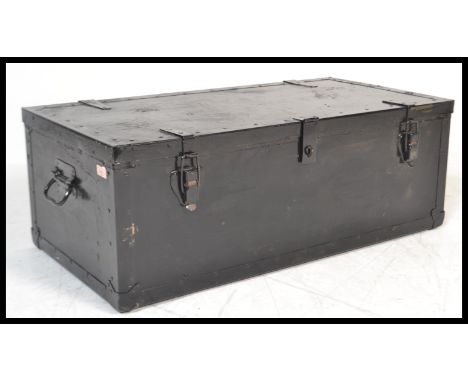 An early 20th century black painted pine and metal bound hinge top travelling trunk with swing handles to either.&nbsp;Measur
