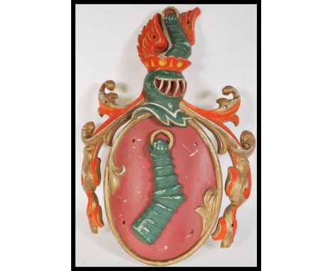 An antique style cast metal Armorial coat of arms / Heraldic crest depicting an embowed arm in armor with hand in gauntlet ho
