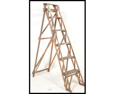 A vintage early 20th Century lattice framed wood Industrial folding step ladder. The six tread ladder having makers plaque Wo