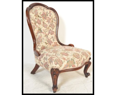 A 19th Century Victorian button backed mahogany nursing chair having carved shaped cabriole legs, upholstered in a floral tap