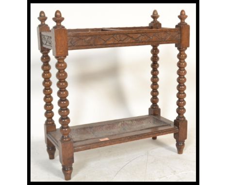 An early 20th Century Edwardian stick stand oak, the twin division with carved rails on turned bobbin uprights retaining orig