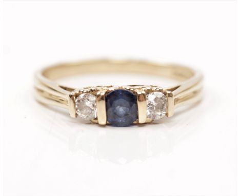 A sapphire and diamond three stone ring, set with a central round cut sapphire, flanked to either side with a round brilliant