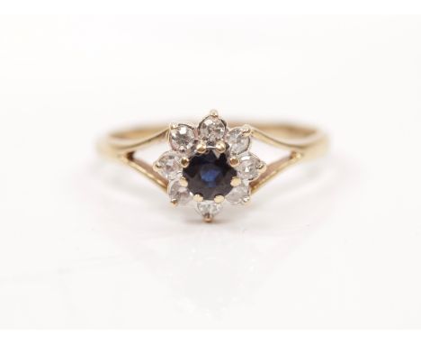 A hallmarked 9ct yellow gold sapphire and diamond cluster ring, set with a central round cut sapphire surrounded by eight sin