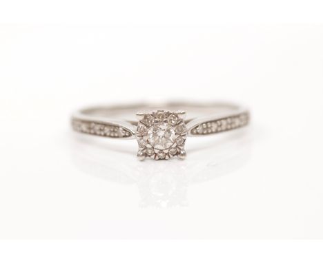 A hallmarked 9ct white gold diamond ring, set with a principal round brilliant cut diamond, surrounded by diamond accents in 