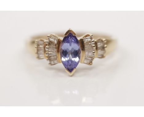 A hallmarked 9ct yellow gold tanzanite and diamond ring, set with a central marquise cut tanzanite flanked to either side wit