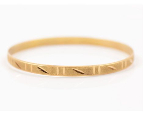 A bright cut engraved and textured bangle, unmarked yellow metal.