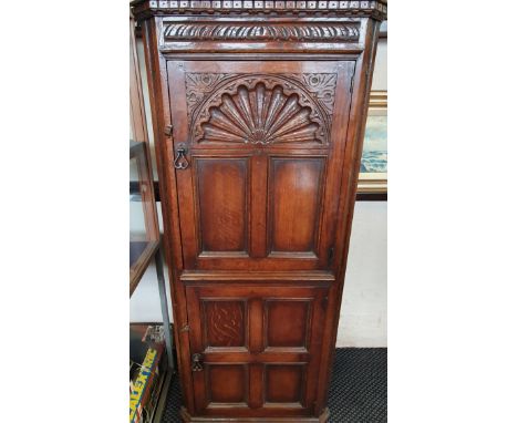 A distressed oak two-door corner cabinet carved panel to front,