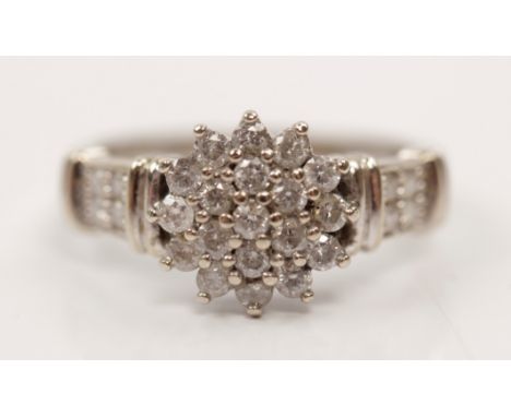 A hallmarked 9ct white gold diamond cluster ring, set with round brilliant cut diamonds to central flower head design, with f