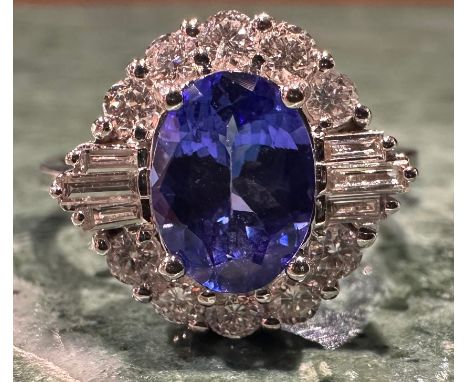 A tanzanite and diamond cluster ring central oval tanzanite approx 1.19ct, surrounded by six baguette and ten round brilliant