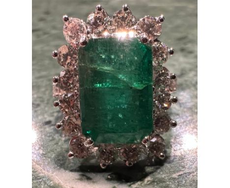 A certified emerald and diamond cluster ring, central Zambian elongated octagonal step cut emerald, 12.74 x 8.83 x 6.10mm, 6.